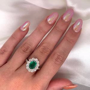 A 1940s emerald and diamond cluster ring with a classic Art Deco design, featuring a central emerald surrounded by a halo of diamonds on a hand.