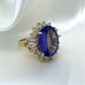 A stunning cocktail ring with a large oval-cut sapphire surrounded by a halo of sparkling diamonds, set in yellow gold.