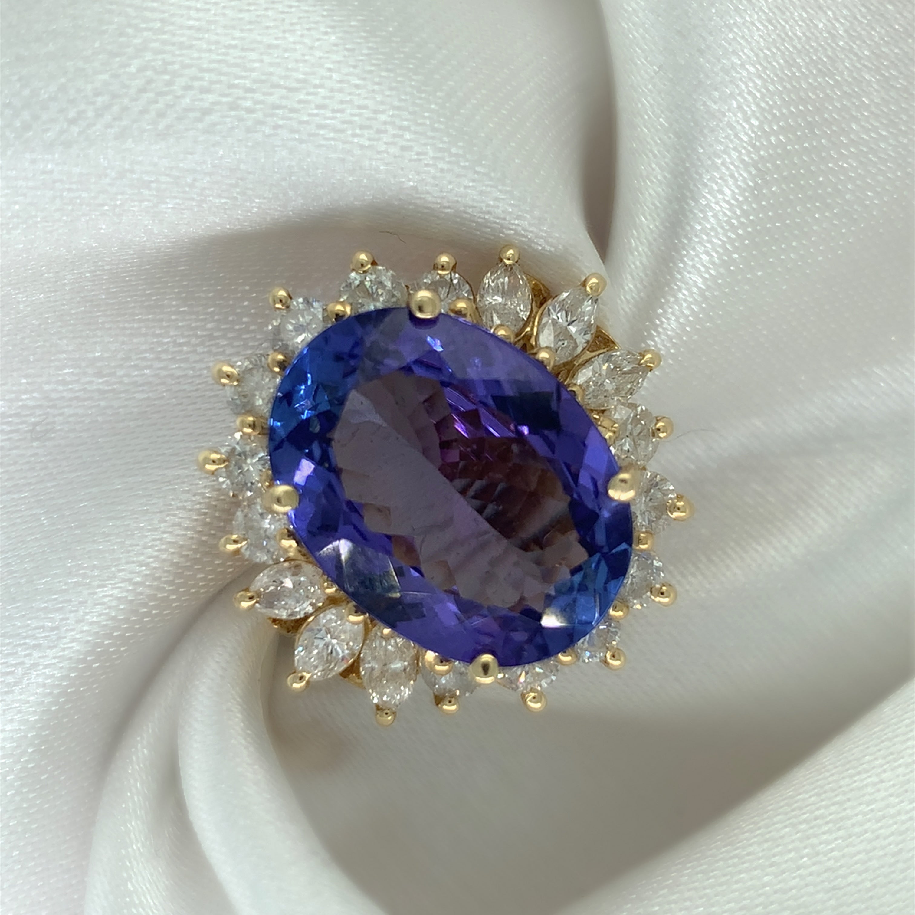A stunning cocktail ring with a large oval-cut sapphire surrounded by a halo of sparkling diamonds, set in yellow gold.