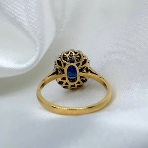 A back view of a 1980s Art Deco ring with a deep blue oval-cut sapphire surrounded by a halo of sparkling diamonds featuring a vibrant sapphire and a platinum and 18ct yellow gold setting