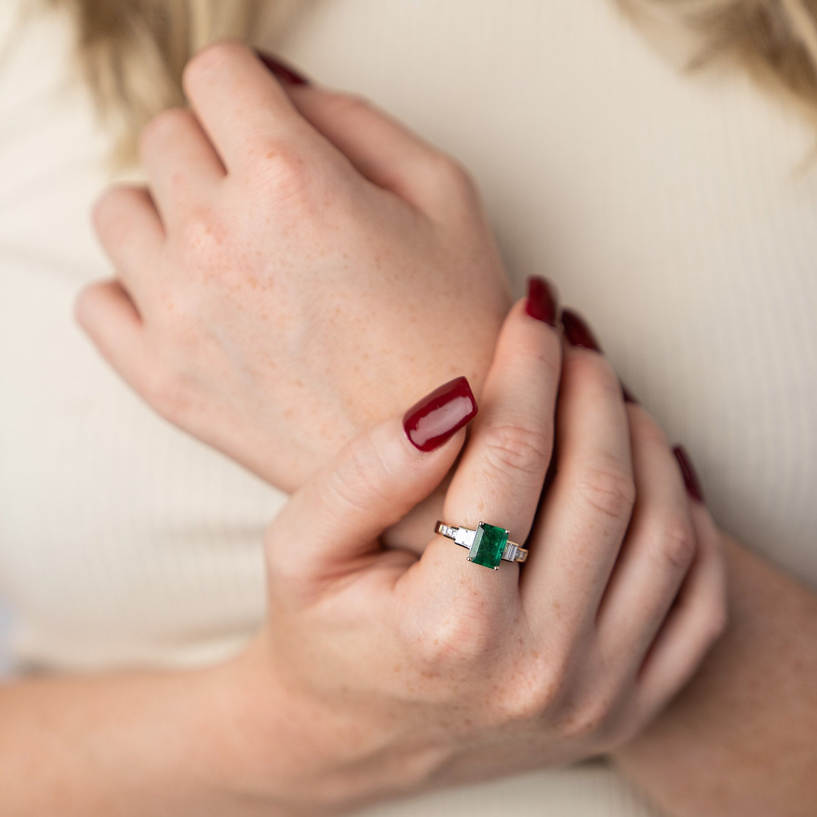 A classic emerald and diamond ring showcasing a rectangular emerald-cut green stone, flanked by baguette diamond side stones on a polished gold band.