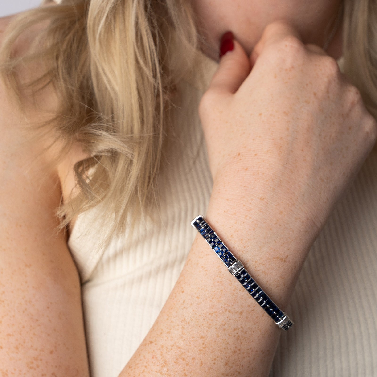 A striking sapphire and diamond channel-set bracelet featuring deep blue square-cut sapphires accented by occasional baguette diamonds, set in white gold.