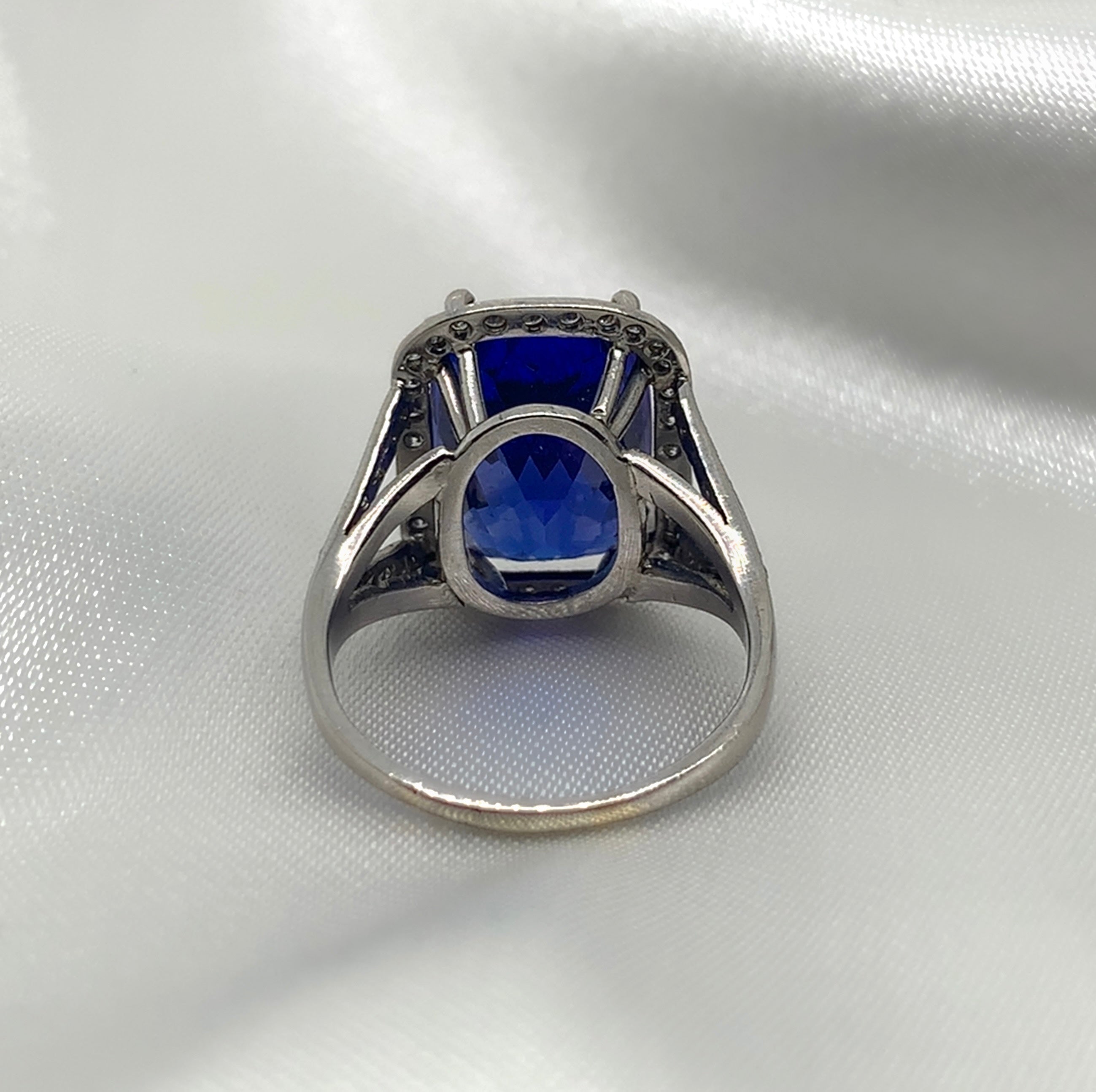 A back view of a stunning radiant-cut tanzanite ring set in platinum with a halo of sparkling diamonds.