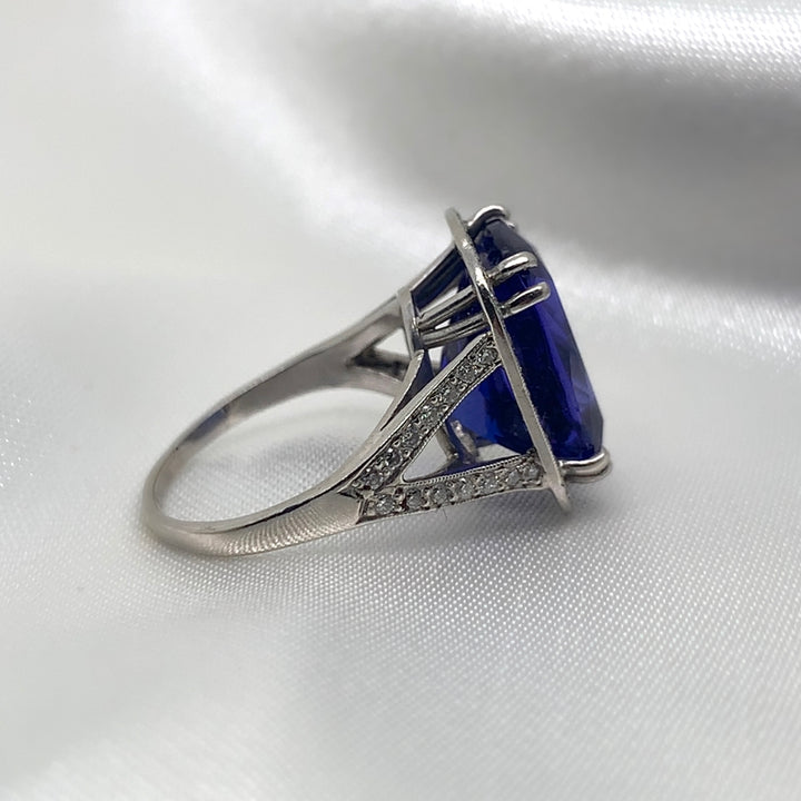 A side view of a stunning radiant-cut tanzanite ring set in platinum with a halo of sparkling diamonds.