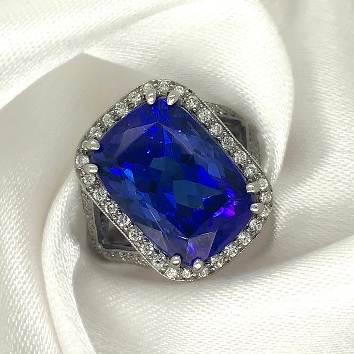 A stunning radiant-cut tanzanite ring set in platinum with a halo of sparkling diamonds.