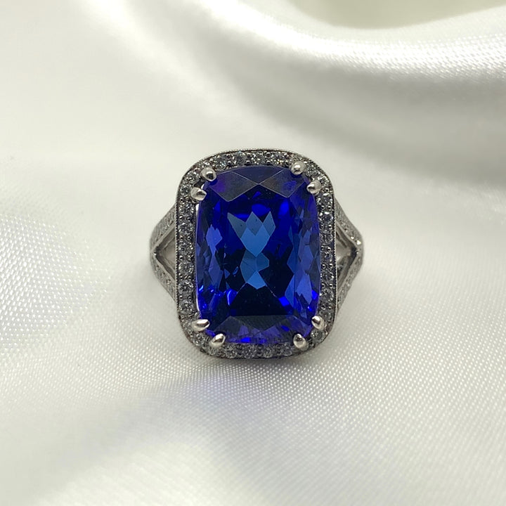 A stunning radiant-cut tanzanite ring set in platinum with a halo of sparkling diamonds.