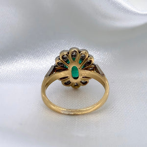 A back view of a 1940s emerald and diamond cluster ring with a classic Art Deco design, featuring a central emerald surrounded by a halo of diamonds.