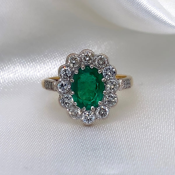 1940s emerald and diamond cluster ring with a classic Art Deco design, featuring a central emerald surrounded by a halo of diamonds.