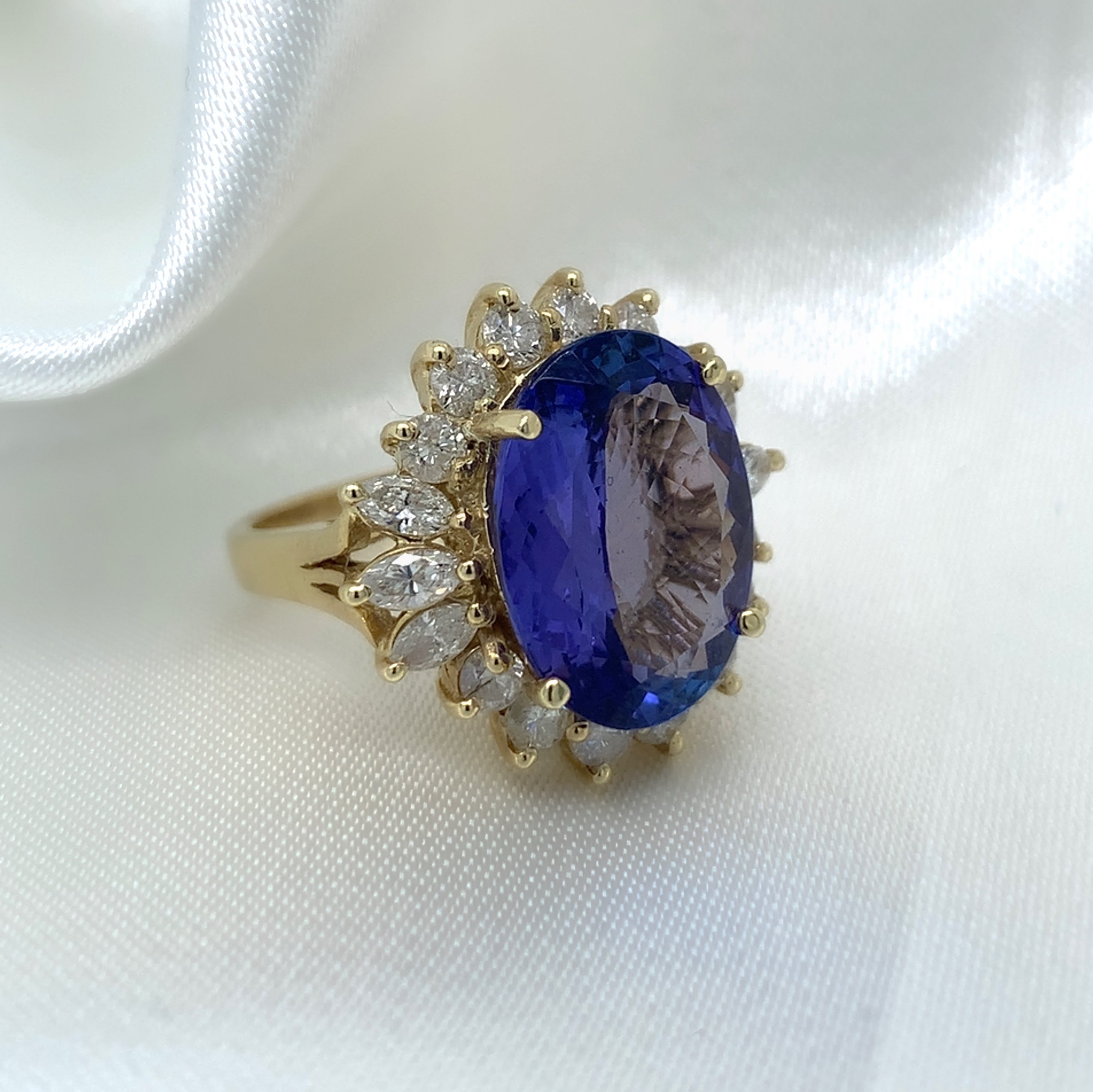 A stunning cocktail ring with a large oval-cut sapphire surrounded by a halo of sparkling diamonds,  set in yellow gold.