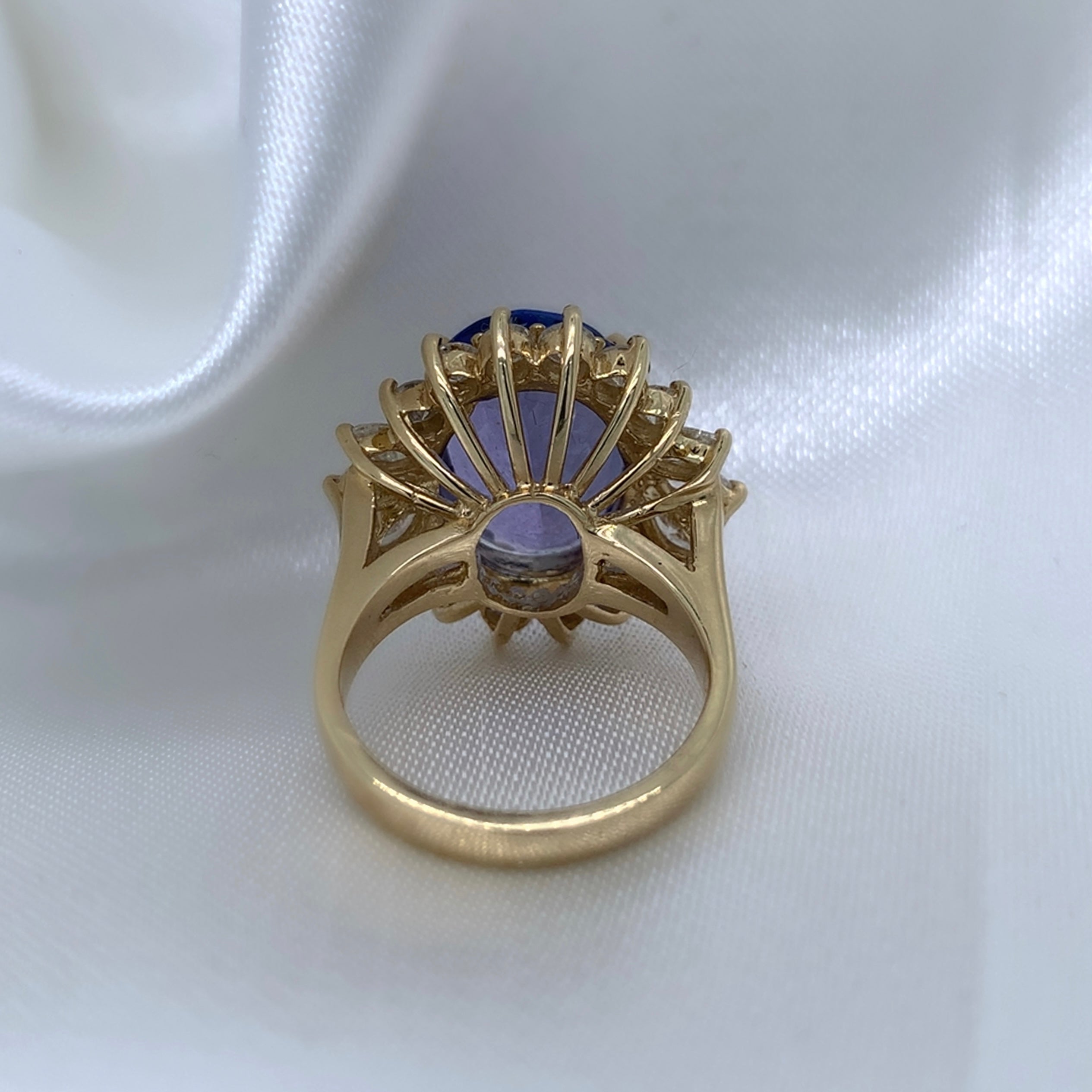 The back of a stunning cocktail ring with a large oval-cut sapphire surrounded by a halo of sparkling diamonds,  set in yellow gold.