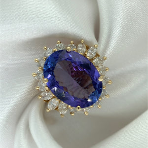 A stunning cocktail ring with a large oval-cut sapphire surrounded by a halo of sparkling diamonds,  set in yellow gold.