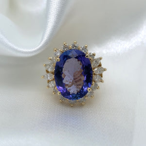 A stunning cocktail ring with a large oval-cut sapphire surrounded by a halo of sparkling diamonds,  set in yellow gold.