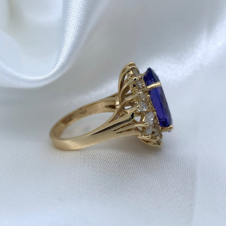 The side of a stunning cocktail ring with a large oval-cut sapphire surrounded by a halo of sparkling diamonds,  set in yellow gold.