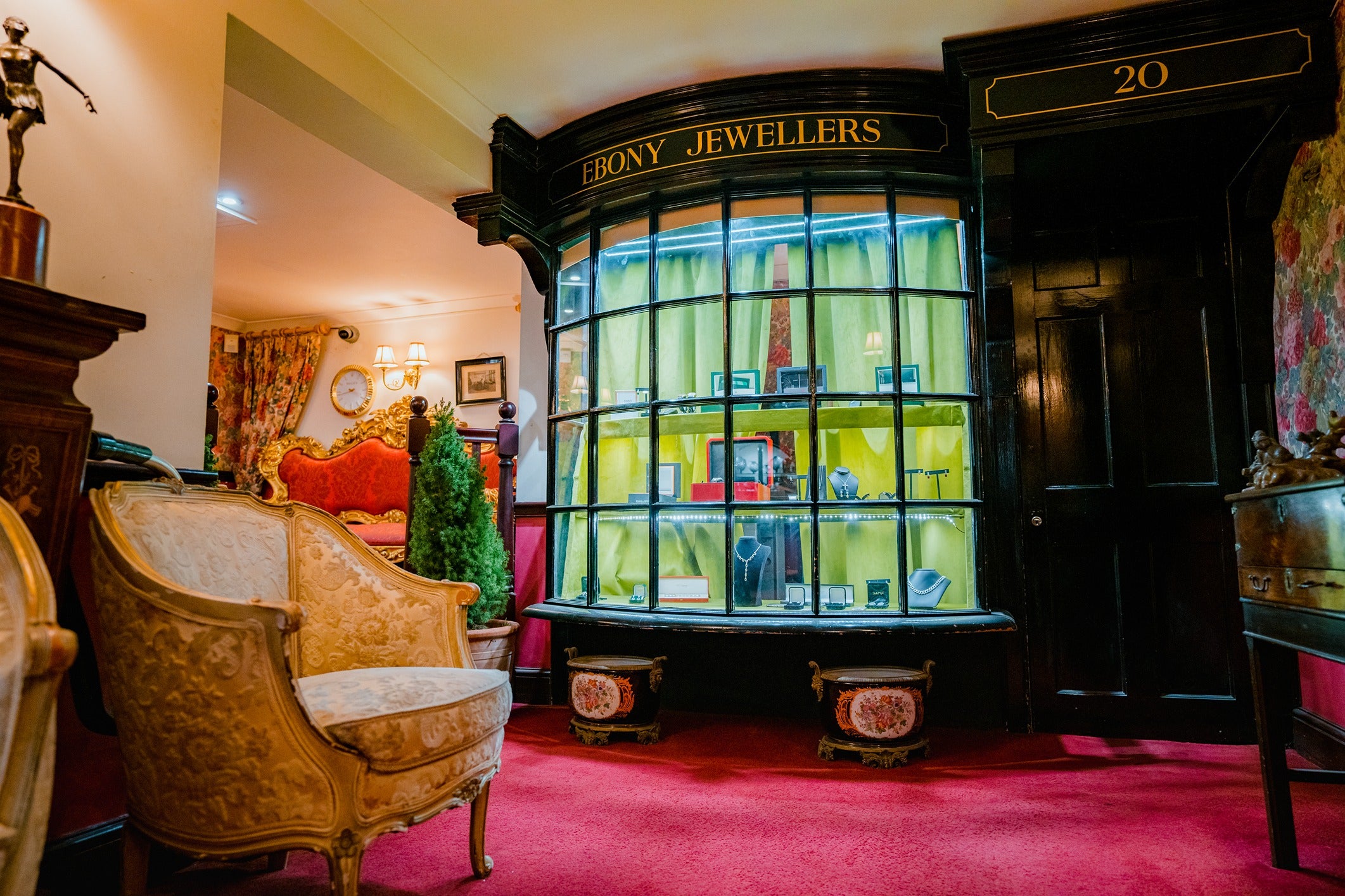 A closer look at the historic Ebony Jewellers shop front from the inside, featuring the bow-fronted window and an antique cream-coloured armchair.