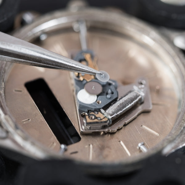 A high-detail, macro shot representing professional watch servicing, showing a pair of precision tweezers carefully placing a tiny gear into the intricate internal movement of a timepiece.